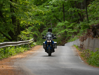 Biker man on a motorcycle in the forest. Travel and sport, speed and freedom concept.
